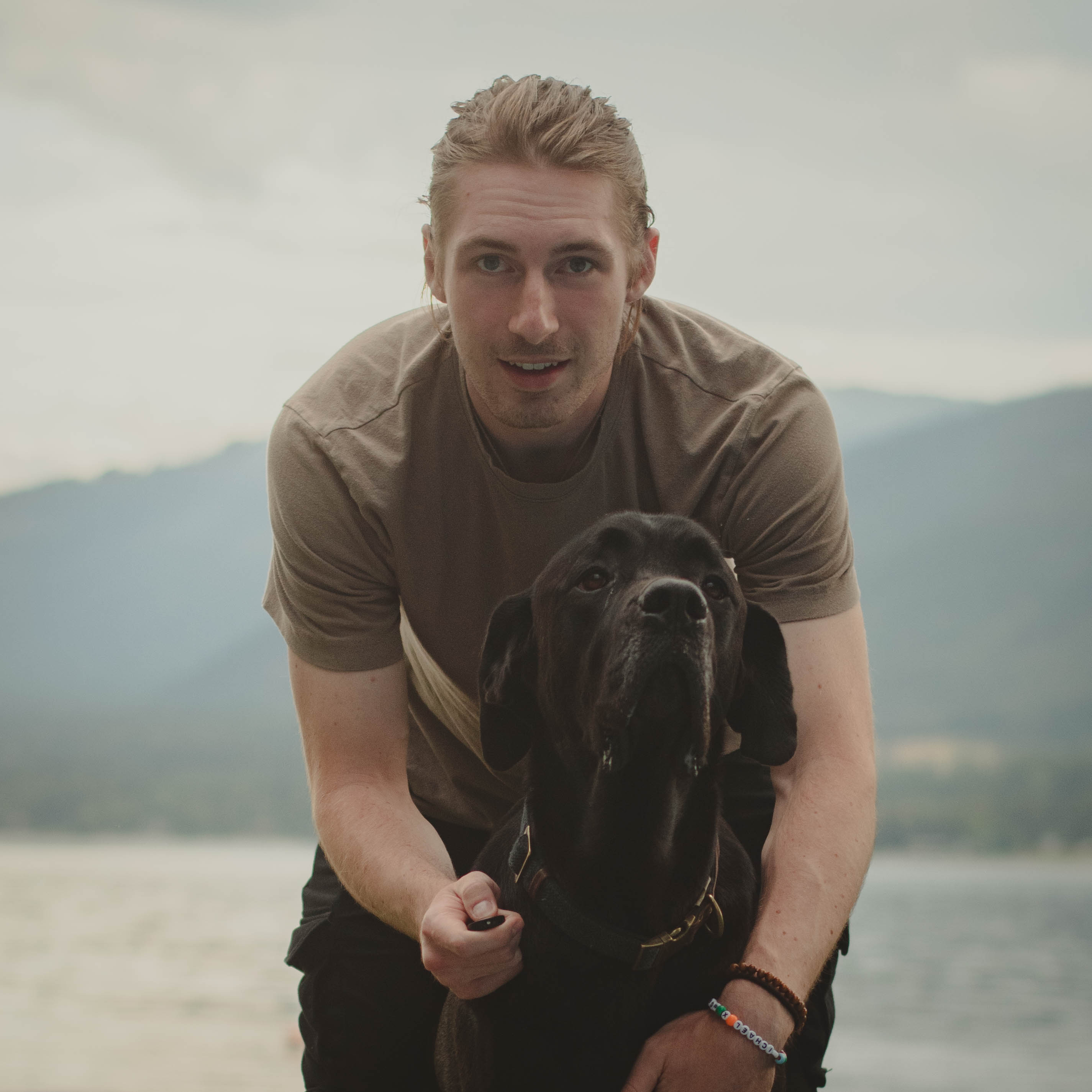 front facing camera of man's face with a large black dog